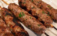 several skewers of meat on a white plate