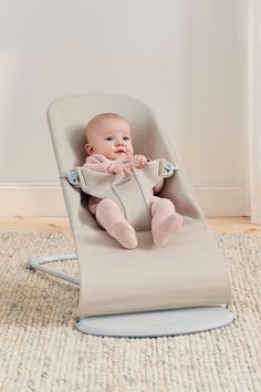 a baby sitting in a bouncer on the floor