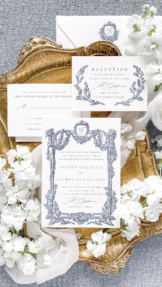 the wedding stationery is laid out on a gold tray with white flowers