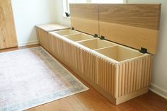 a wooden bench with drawers on it in front of a rug and window sill