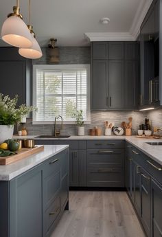 a kitchen with gray cabinets and white counter tops, gold accents on the light fixture