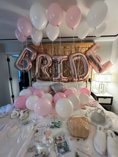 a bed topped with lots of pink and white balloons that spell out the word bride