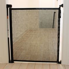 an open door with a screen on the inside of it in a room that has wood floors and white walls