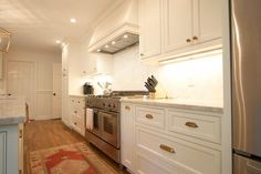 a kitchen with white cabinets and stainless steel appliances, including an oven in the center