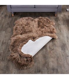 a brown and white rug on the floor with a couch in the back ground next to it