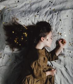 a woman laying on top of a bed covered in stars