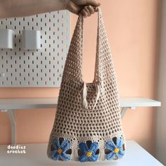 a crocheted purse with blue flowers on the bottom is being held by a person