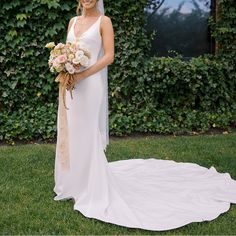 a woman in a white dress holding a bouquet and posing for a photo on her wedding day