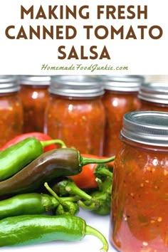 jars filled with red and green peppers sitting on top of a white table next to each other