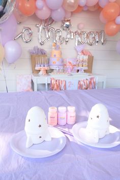 two white plates on a purple table cloth with balloons and confetti in the background