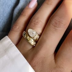 a woman's hand with two wedding rings on her left and the other hand holding an engagement ring