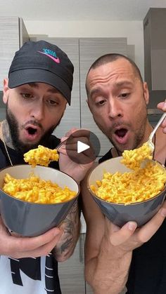 two men holding bowls of macaroni and cheese