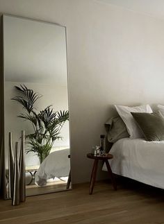 a bedroom with a large mirror on the wall next to a bed and side table