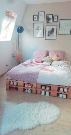 a bed made out of wooden pallets in a room with pictures on the wall