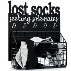 a black basket filled with clothes next to a sign that says lost socks seeking sematies