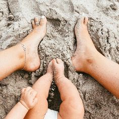 two people are laying in the sand with their feet on each other's legs