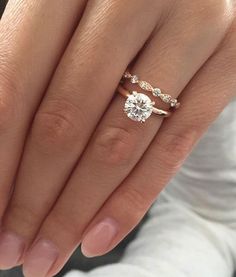 a woman's hand with two engagement rings on it and the other hand holding an engagement