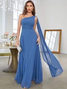 a woman in a blue dress standing next to a table with a chandelier