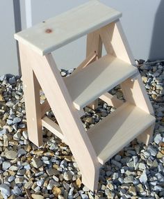 a wooden step stool sitting on top of gravel