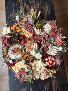 an assortment of cheeses, meats and vegetables arranged in a circle on a table