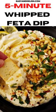 a hand dipping a tortilla chip into a bowl filled with feta dip