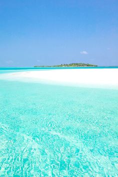 an island in the middle of clear blue water with white sand on it's bottom