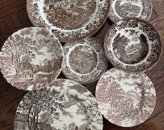 several plates with trees and buildings on them sitting on a wooden table next to each other