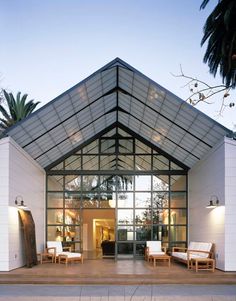 the front entrance to a modern house with large glass doors and white furniture on wooden steps