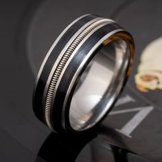 a black and white wedding band with silver inlays is shown on top of a table