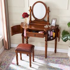 a wooden vanity table with a mirror and stool in front of a potted plant