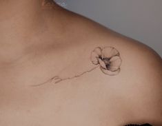 a woman's chest with a flower tattoo on the left side of her breast