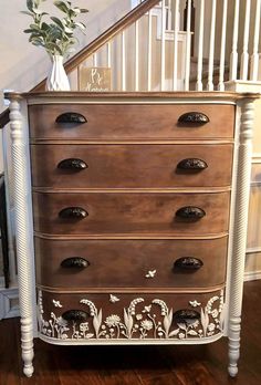 an old dresser has been painted with white paint and flowers on the bottom, as well as