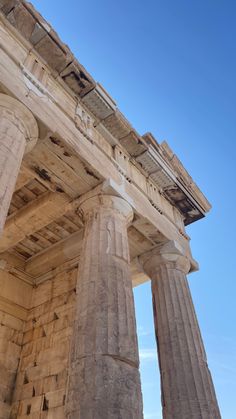 an old stone building with columns on the outside and blue sky in the back ground