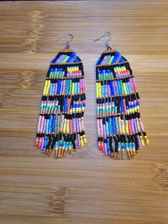 a pair of colorful beaded earrings sitting on top of a wooden table