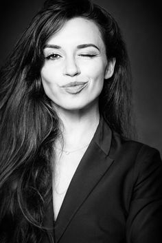 a black and white photo of a woman with long dark hair, smiling at the camera