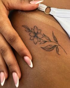 a woman's stomach with flowers and leaves tattoo on her left side ribcage