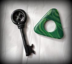 a green and black key laying on top of a white sheet next to a bottle opener