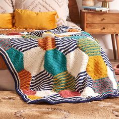 a crocheted blanket on a bed in a room with wooden furniture and pillows