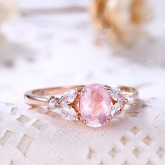 a close up of a ring on a lace table cloth with flowers in the background