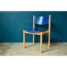 a blue chair sitting in front of a green wall with a wooden frame and seat