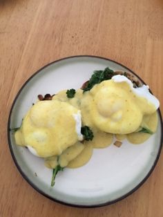 two eggs benedicts on a plate with mushrooms and spinach