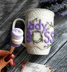 a lady's boss coffee mug with purple flowers on it and a matchbox