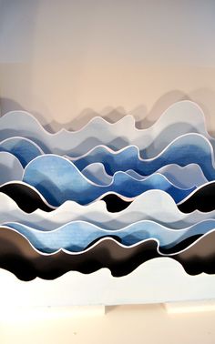 an abstract painting with blue and black waves on the bottom, against a white wall