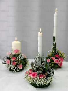 three candles are sitting on a table with flowers and greenery