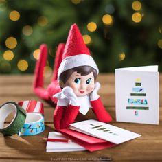 an elf is sitting next to some christmas cards