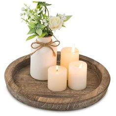 three candles are sitting on a wooden tray