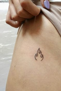 a woman's stomach with a small tattoo on her lower back and the word fire written in black ink