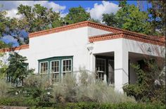 a white house surrounded by trees and bushes