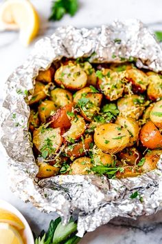 cooked potatoes in foil with parsley and lemon wedges on the side for garnish