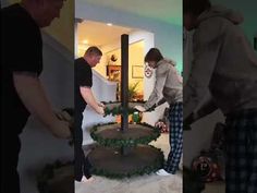 two men are decorating a three - tiered cake with greenery on it